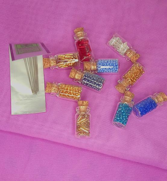 Set of 10 glass bottles of seed beads and 10 needles
